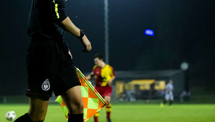 Football assistant referee running along touchline during match